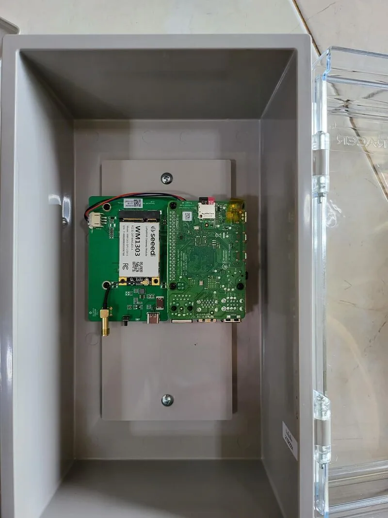 LoRaWAN gateway board and radio module mounted inside an enclosure with a transparent lid.