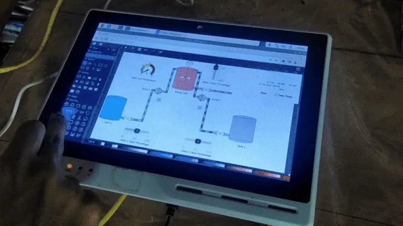 Laptop displaying a process-control diagram with connected tanks, pipes, and equipment, from Southern IoT’s Facebook archive.